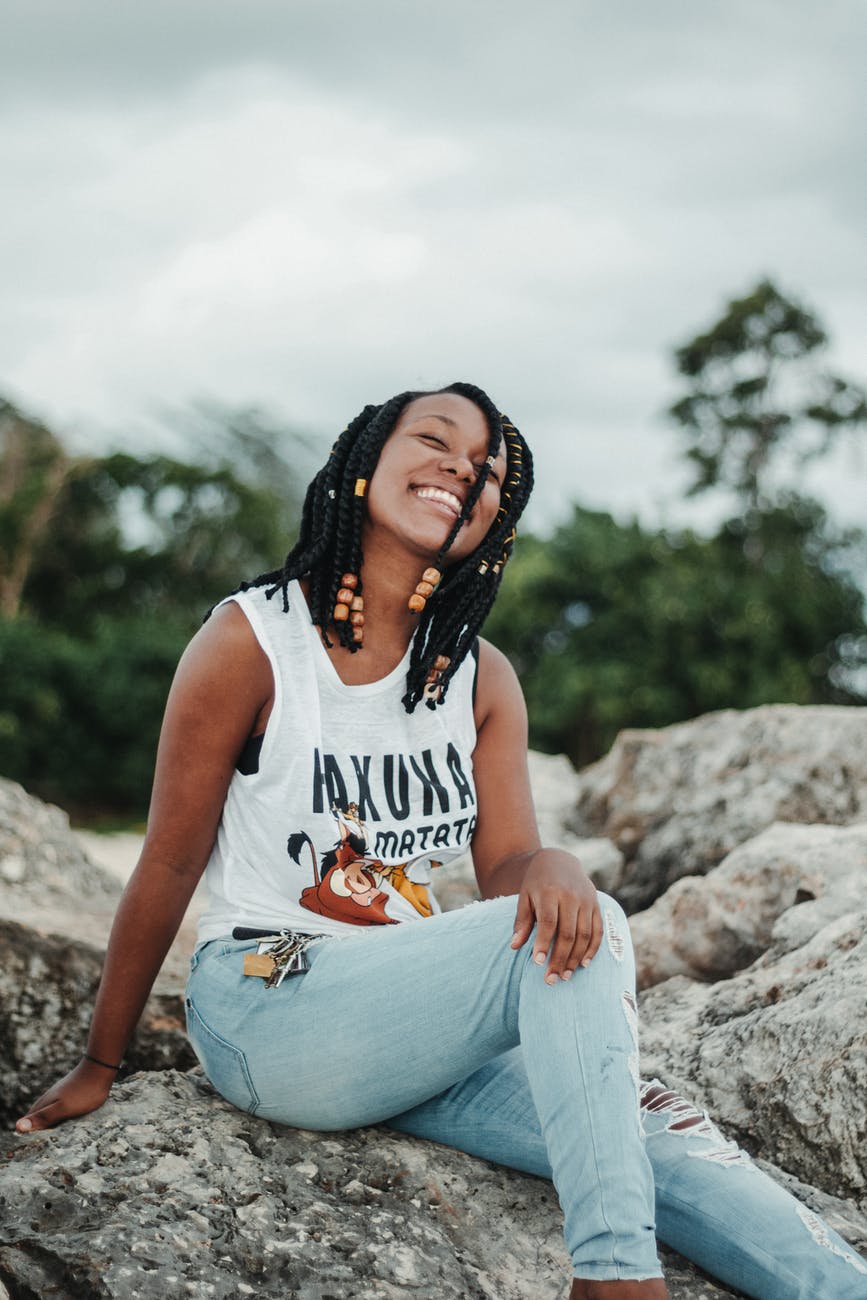 happy ethnic woman in trendy wear resting on mount