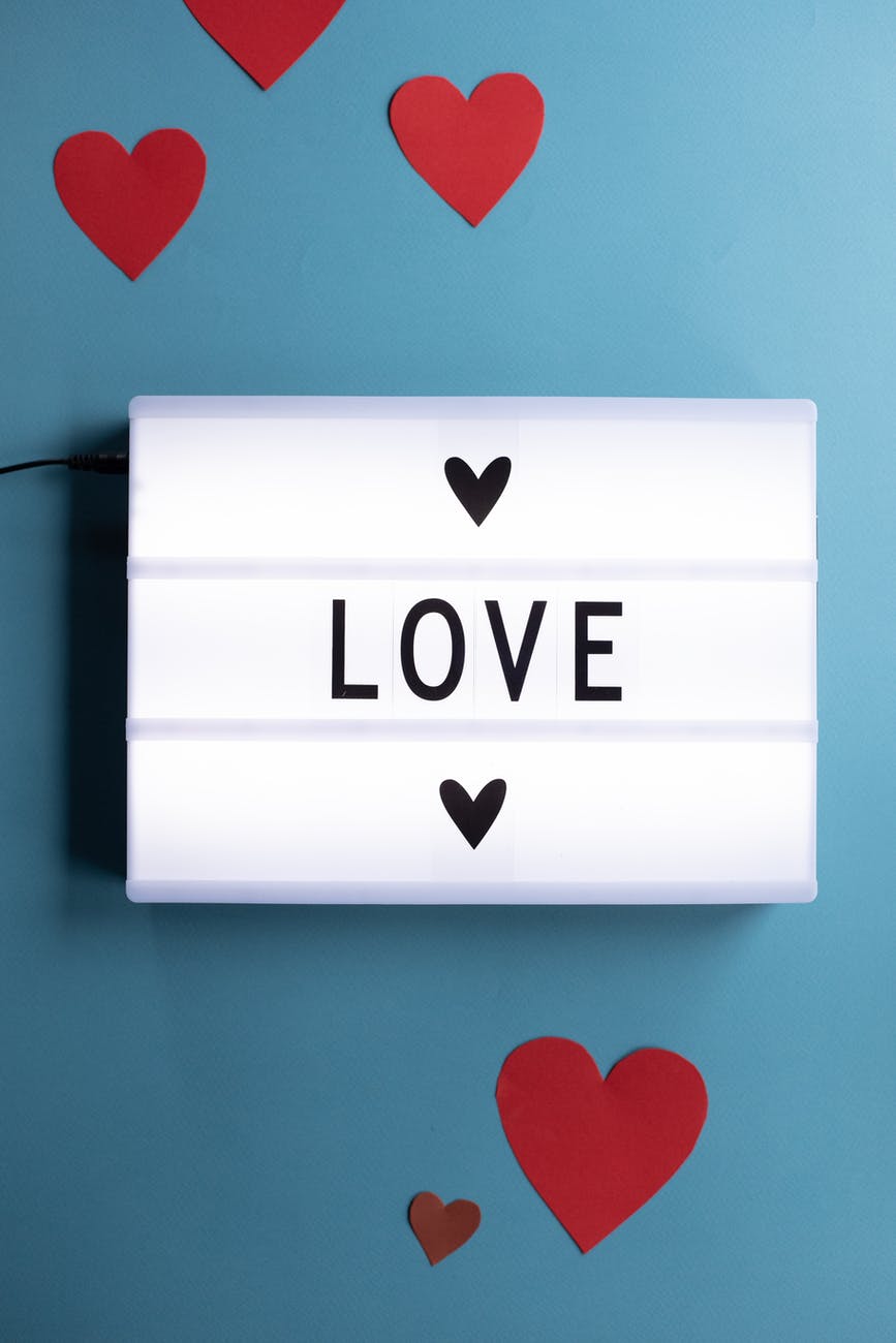 paper hearts around love inscription on light box