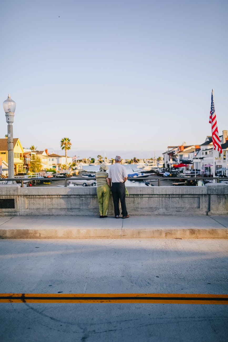 elderly people standing on a bridge above a river
