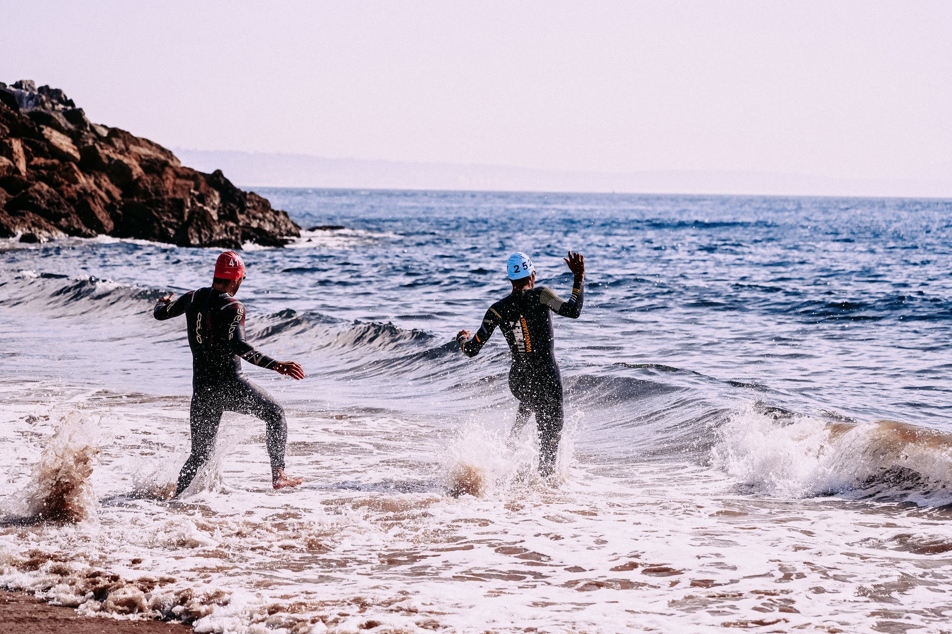 anonymous sportspeople running into sea